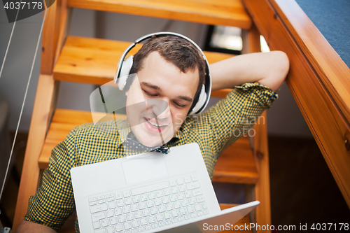 Image of Man entertaining with laptop and music at home 