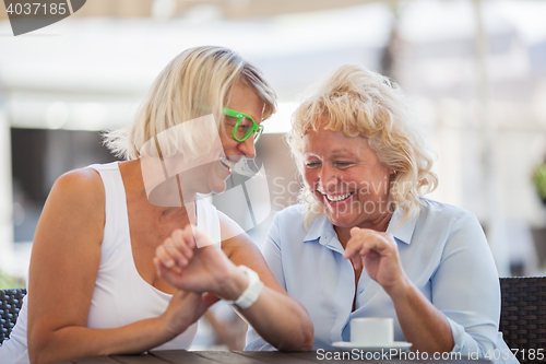 Image of Senior women laughing in street cafe