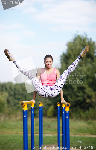 Image of Athletic gymnast exercising on parallel bars