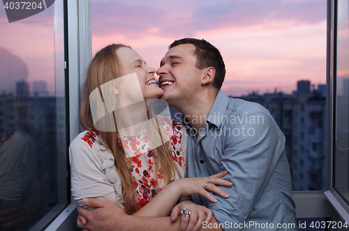 Image of Young couple on the balcony embracing and laughing