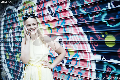 Image of Woman chatting on her mobile in front of graffiti