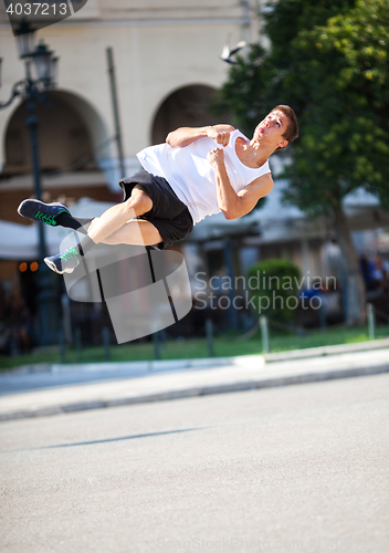 Image of Young man performing somersault in the street