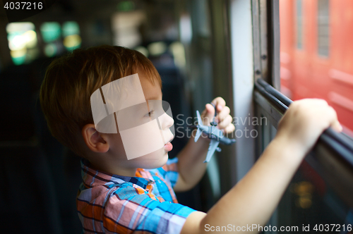 Image of Little boy with toy looking out of train window