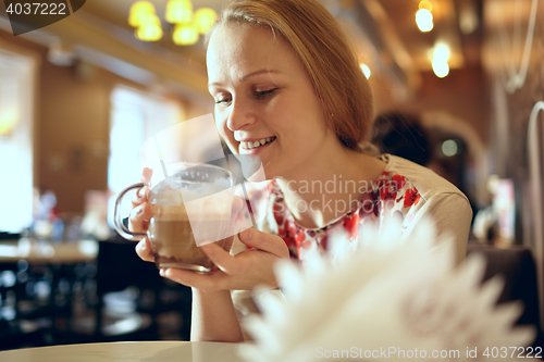 Image of Girl is drinking latte in cafe.