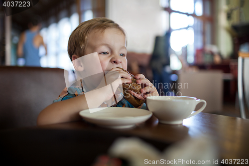 Image of Little boy having sandwich in a cafe