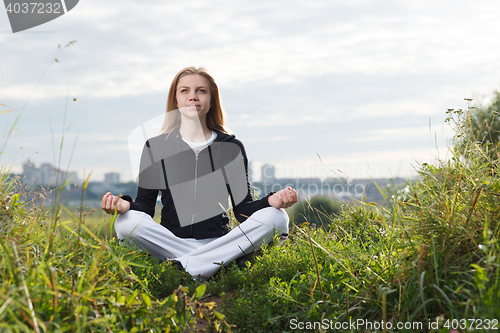 Image of Young girl makes yoga exercises outdoors.