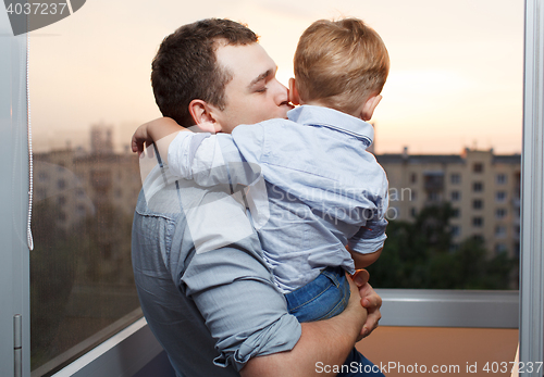 Image of Father kisses his son on the balcony