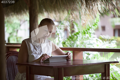 Image of Smiling woman using tablet computer in cafe during vacation