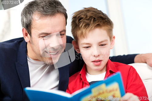 Image of Dad and son reading a book at home