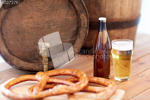 Image of close up of beer barrel, glass, pretzel and bottle