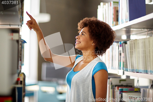 Image of african student girl pointing to book at library
