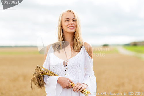 Image of happy young woman with spikelets on cereal field