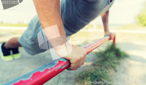 Image of young man exercising on horizontal bar outdoors