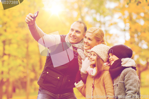 Image of happy family with camera in autumn park