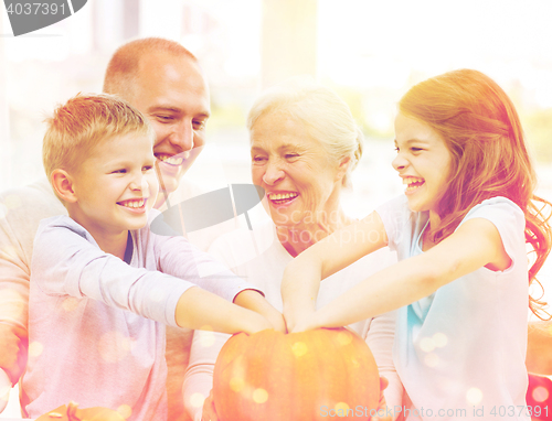 Image of happy family sitting with pumpkins at home