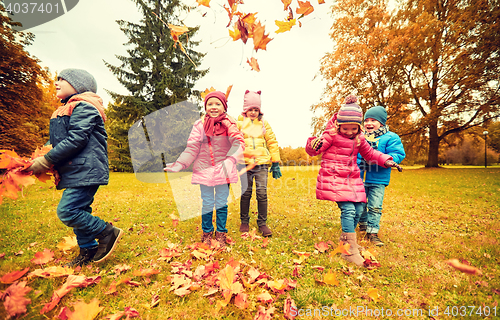 Image of happy children playing with autumn leaves in park