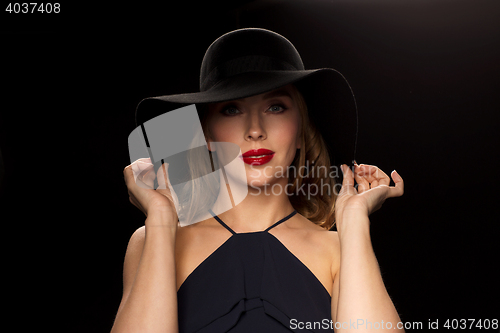 Image of beautiful woman in black hat over dark background