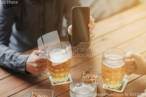 Image of close up of friends with smartphone and beer