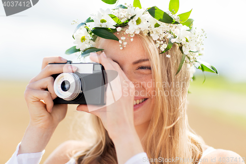 Image of happy woman with film camera in wreath of flowers