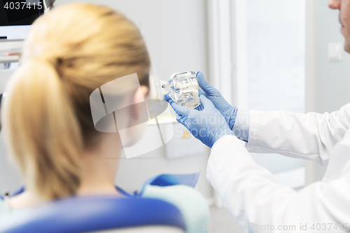 Image of close up of dentist showing teeth model to patient