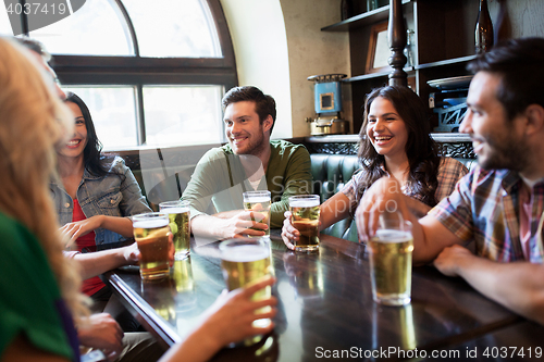 Image of happy friends drinking beer at bar or pub