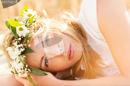 Image of happy woman in wreath of flowers on cereal field