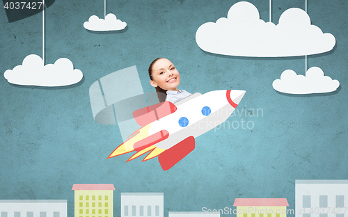 Image of businesswoman flying on rocket above cartoon city