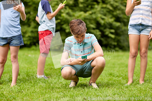 Image of kids with smartphones playing game in summer park