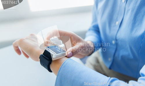 Image of close up of hands with weather cast on smart watch