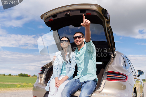 Image of happy couple hugging at open hatchback car trunk