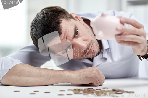 Image of businessman with piggy bank and coins at office