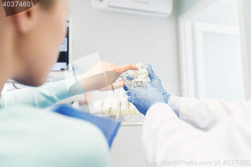 Image of close up of dentist with teeth model and patient