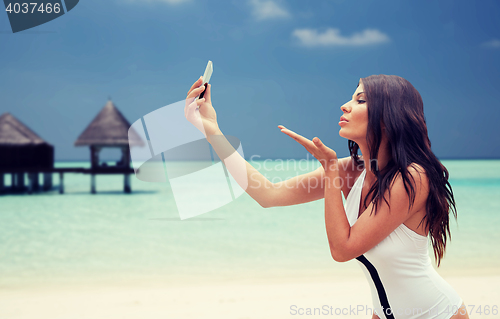 Image of young woman taking selfie with smartphone