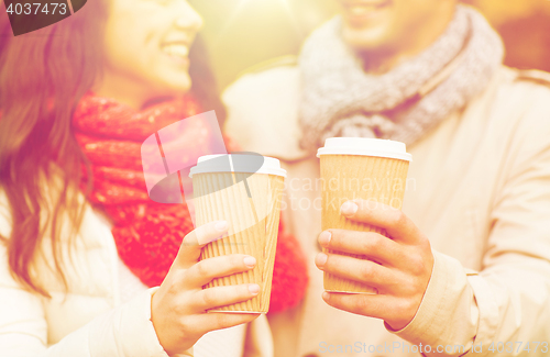 Image of smiling couple with coffee cups in autumn park