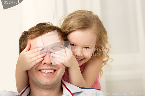 Image of Daughter playing with father closing his eyes