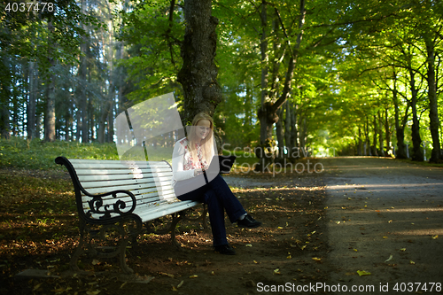 Image of Young woman with laptop in the park