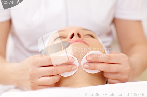 Image of Cosmetician cleaning face using cotton pads