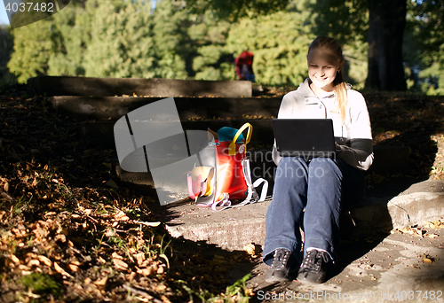 Image of Young woman working outdoors on a laptop