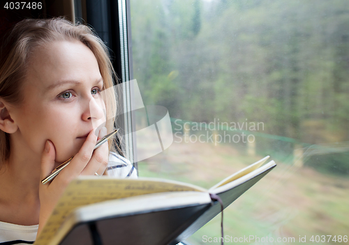 Image of Young woman on a train writing notes