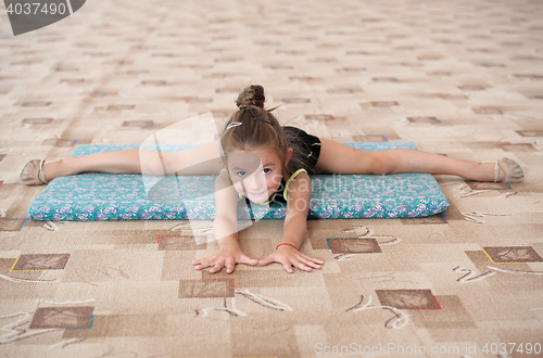 Image of Little girl doing leg-split on the floor