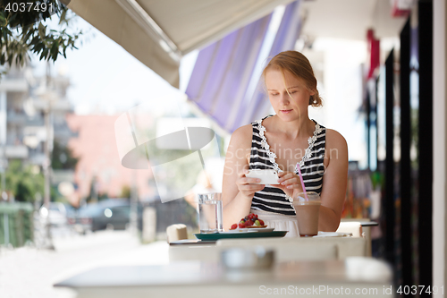 Image of Woman with phone in outdoor cafe