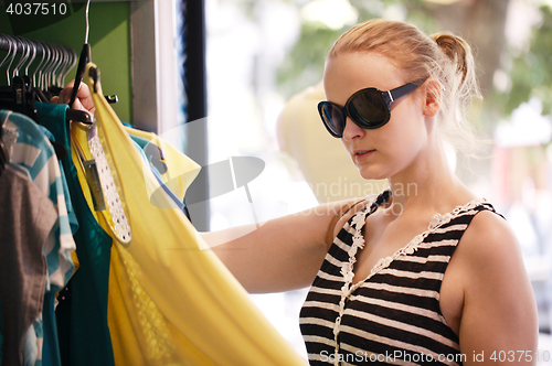 Image of Young girl chooses dress in shop