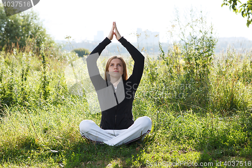 Image of Young woman practicing yoga in the city park