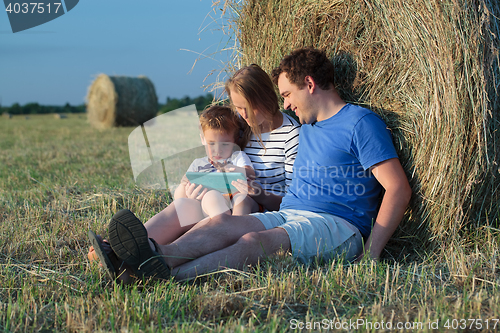 Image of Family of three with pad in the field with hay rolls