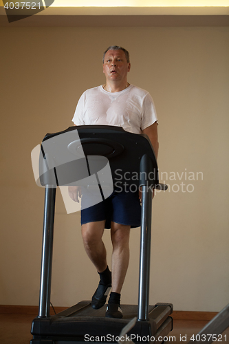 Image of Middle-aged man working out on a treadmill