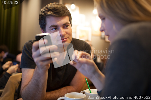 Image of Man using mobile phone during meeting with girl in cafe