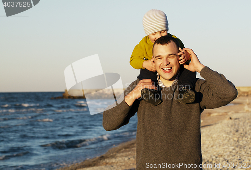 Image of Laughing father giving his sonny a piggy back