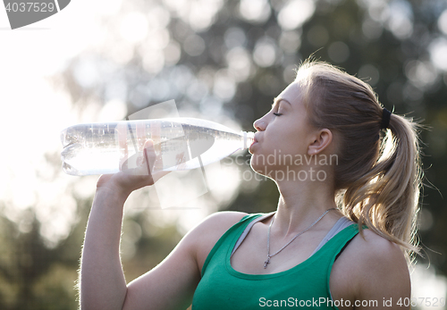 Image of Young woman drinking water after fitness