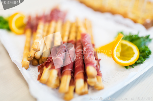 Image of close up of grissini bread sticks with prosciutto