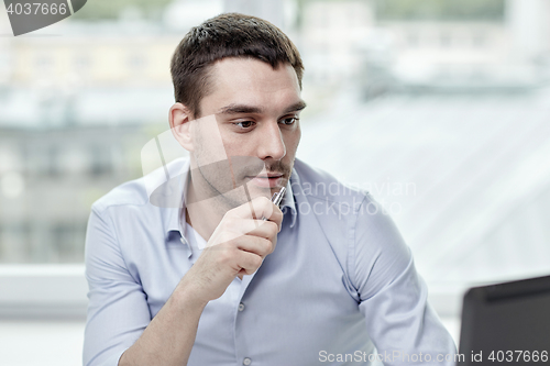 Image of young businessman with laptop computer at office